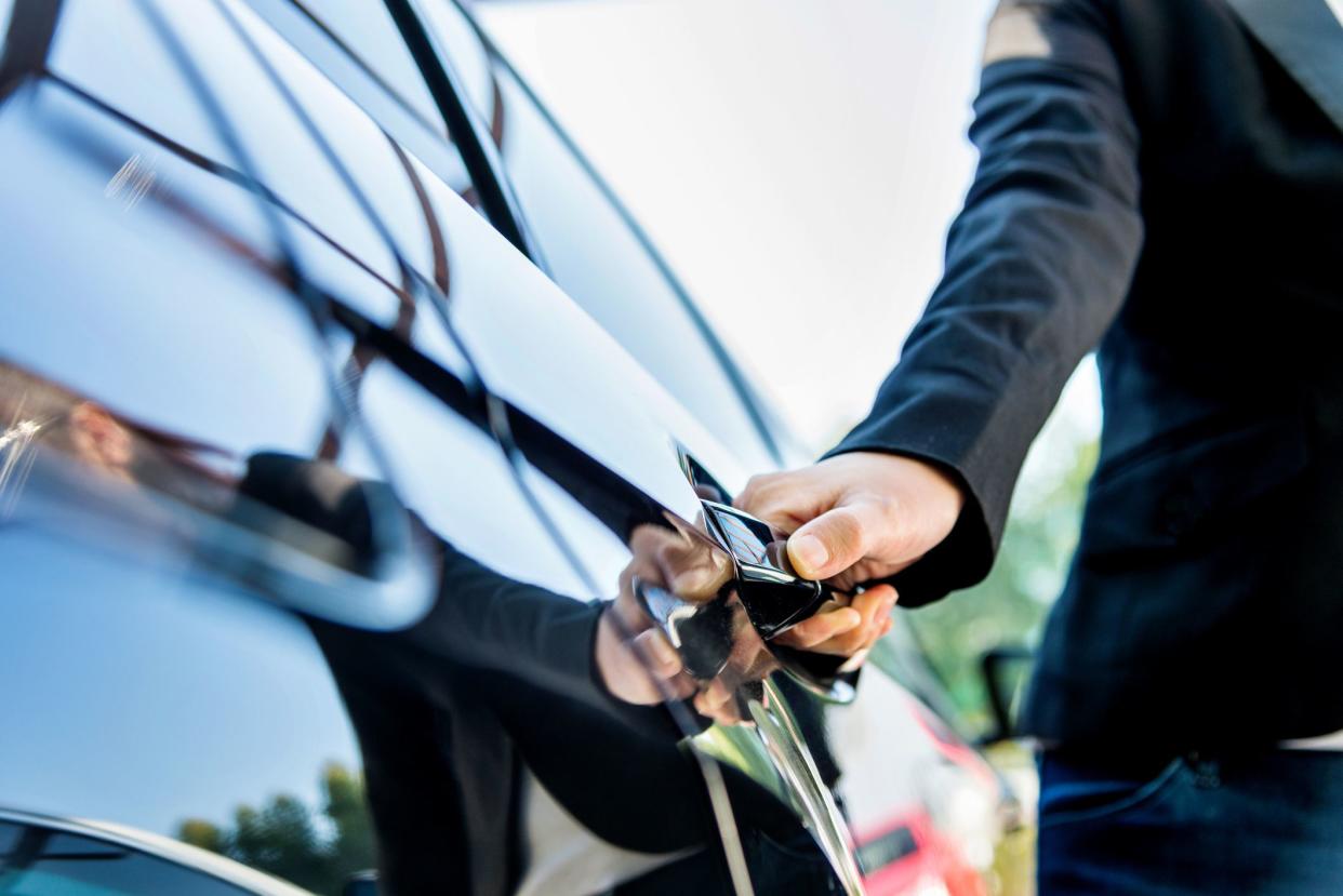 Female chauffeur opening a luxury car door.