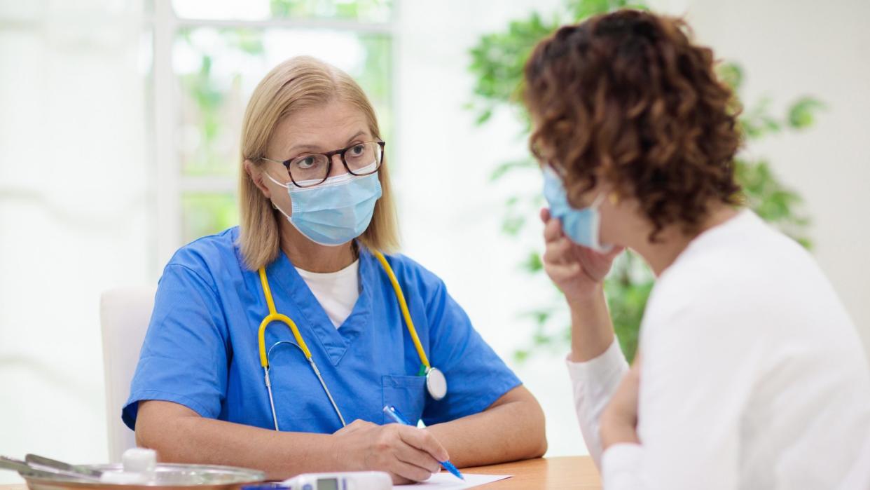 Doctor examining sick patient in face mask.