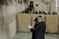 Canada's Prime Minister Stephen Harper (R) looks at a Bible with Western Wall Rabbi Shmuel Rabinowitz as they stand in front of the Western Wall, Judaism's holiest prayer site, during his visit to Jerusalem's Old City January 21, 2014. Harper told Israel's parliament on Monday any comparison between the Jewish state and apartheid South Africa was "sickening", drawing a standing ovation - and an angry walkout by two Arab legislators. REUTERS/Ammar Awad (JERUSALEM - Tags: POLITICS)