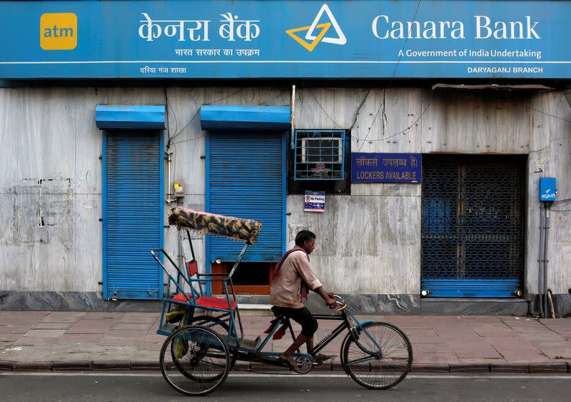 FILE PHOTO: A rickshaw puller passes the Canara Bank branch in the old quarters of Delhi