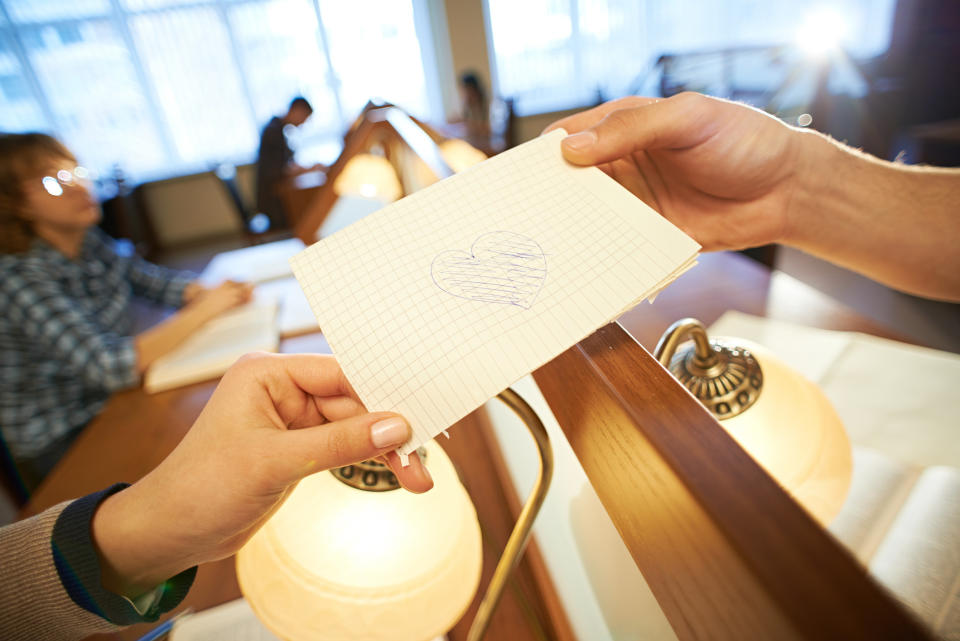 hands holding a paper with a heart drawn on it