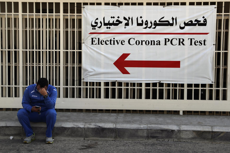 A man checks his mobile phone as he sits near the emergency entrance of the coronavirus testing center at the Rafik Hariri University Hospital in Beirut, Lebanon, Monday, Jan. 11, 2021. Lebanon's caretaker prime minister said Monday the country has entered a "very critical zone" in the battle against coronavirus as his government mulls tightening nationwide lockdown announced last week. (AP Photo/Bilal Hussein)