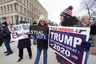 Protesters hold signs outside the Richard H. Austin state office building during a rally in Lansing, Mich., Saturday, Nov. 14, 2020. Michigan's elections board is meeting to certify the state's presidential election results. (AP Photo/Paul Sancya)