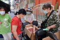 Street vendor Shan Peng attends to customers at her food stall set up on an electric tricycle outside a residential compound in Beijing