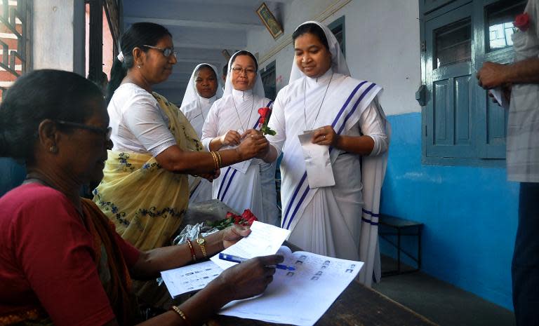 An Indian election official distributes red roses to Christian nuns during voter registration in Ranchi on April 17, 2014