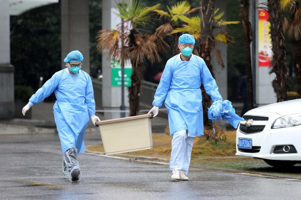 Medical staff carry a box as they walk at the Jinyintan hospital (REUTERS)