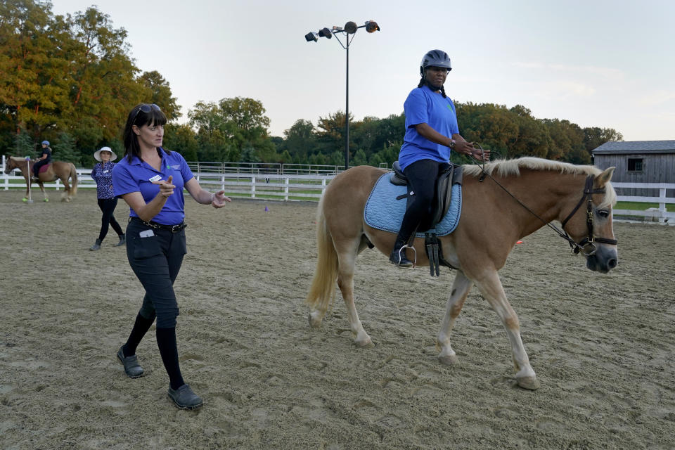 Dionne Williamson, right, of Patuxent River, Md., takes instruction from Equine Coordinator Clarice Gutman, left, during a riding lesson at Cloverleaf Equine Center in Clifton, Va., Tuesday, Sept. 13, 2022. After finishing a tour in Afghanistan in 2013, Williamson felt emotionally numb. As the Pentagon seeks to confront spiraling suicide rates in the military ranks, Williamson’s experiences shine a light on the realities for service members seeking mental health help. For most, simply acknowledging their difficulties can be intimidating. And what comes next can be frustrating and dispiriting. (AP Photo/Susan Walsh)