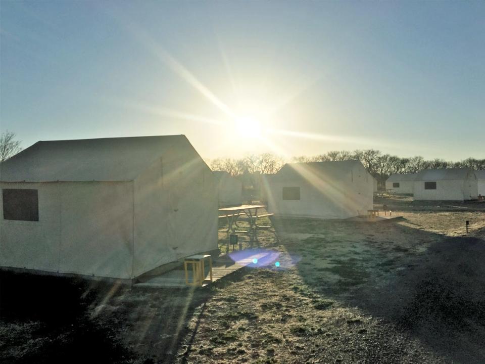 Sun shining through tents at a campsite with tents.