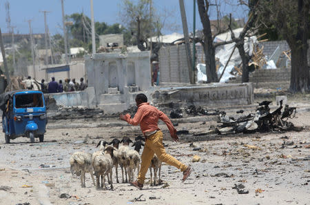 A man runs past the wreckage of a suicide car explosion and sheep after al-Shabaab militia stormed a government building in Mogadishu, Somalia March 23, 2019. REUTERS/Feisal Omar