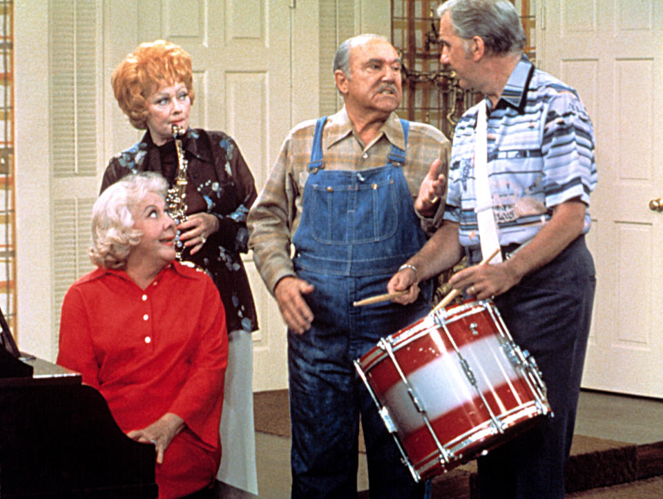 Lucille Ball plays the clarinet, Gale Gordon wears overalls, Vivian Vance sits at the piano, and William Frawley holds a drum in a comedic scene from "The Lucy Show."