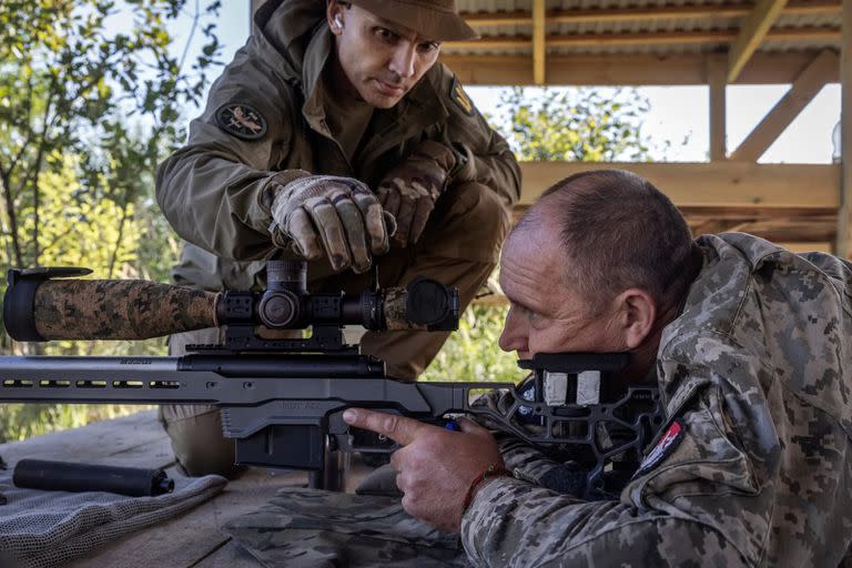 Un instructor, a la izquierda, ayuda a Volodymyr, de 54 años, un soldado de infantería que asistía a su primer día de entrenamiento de francotirador en un campo de tiro