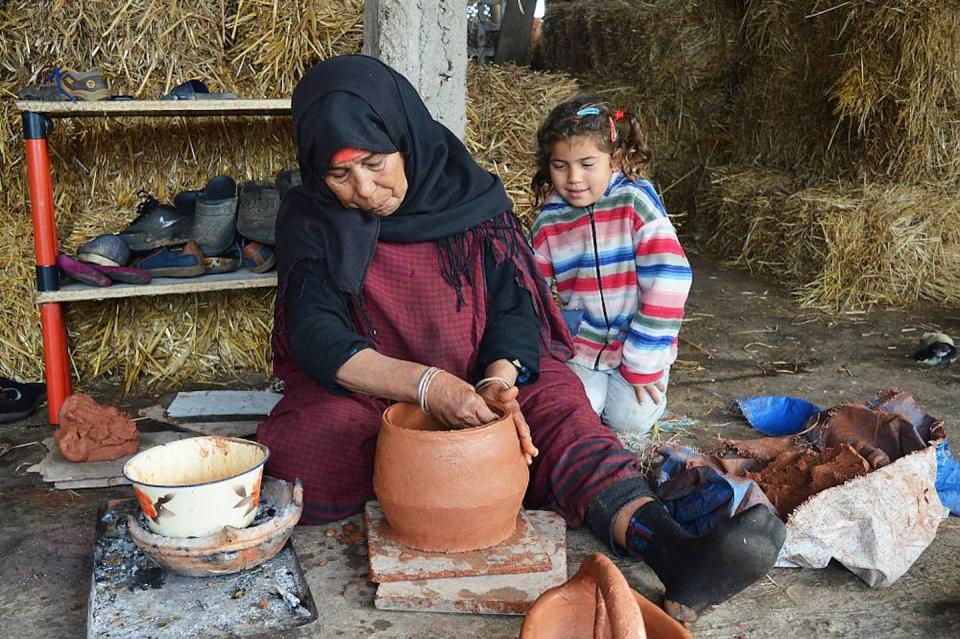 Una mujer trabaja la cerámica ante la mirada de una niña