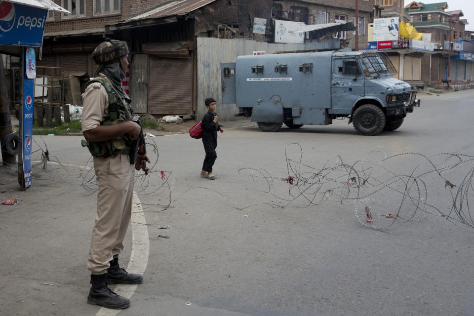 In this Tuesday, Aug. 6, 2019 photo, a Kashmiri boy walks past an Indian Paramilitary soldier after buying fresh bread during curfew in Srinagar, Indian controlled Kashmir, Wednesday, Aug. 7, 2019. Authorities in Hindu-majority India clamped a complete shutdown on Kashmir as they scrapped the Muslim-majority state's special status, including exclusive hereditary rights and a separate constitution, and divided it into two territories. (AP Photo/Dar Yasin)