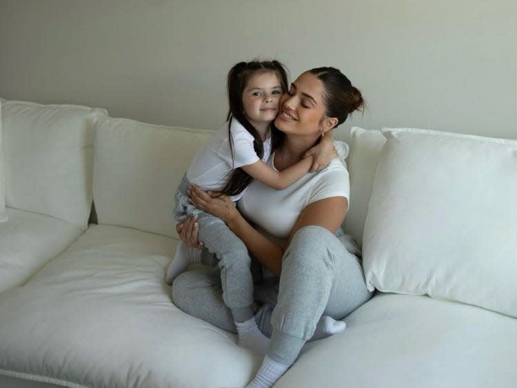 LaPalomento with her daughter, Giada, sitting on a white couch.