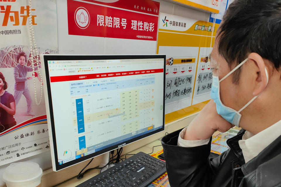 SHANGHAI, CHINA - NOVEMBER 25, 2022 - People buy World Cup soccer lottery at a Chinese sports lottery site in Shanghai, China, November 25, 2022. Outside the store, a red poster with the slogan 