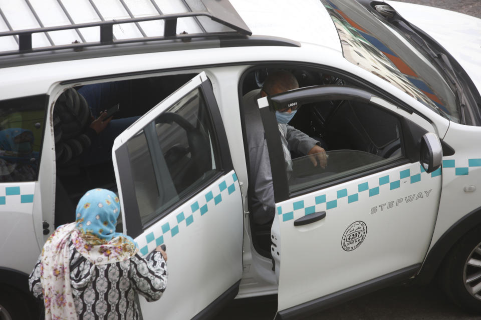 People wear face masks and take a taxi in Casablanca, Morocco, Tuesday, April 6, 2021. Moroccan authorities have announced the discovery of a new local variant of the coronavirus and extended an overnight curfew as infections rise again. (AP Photo/Abdeljalil Bounhar)