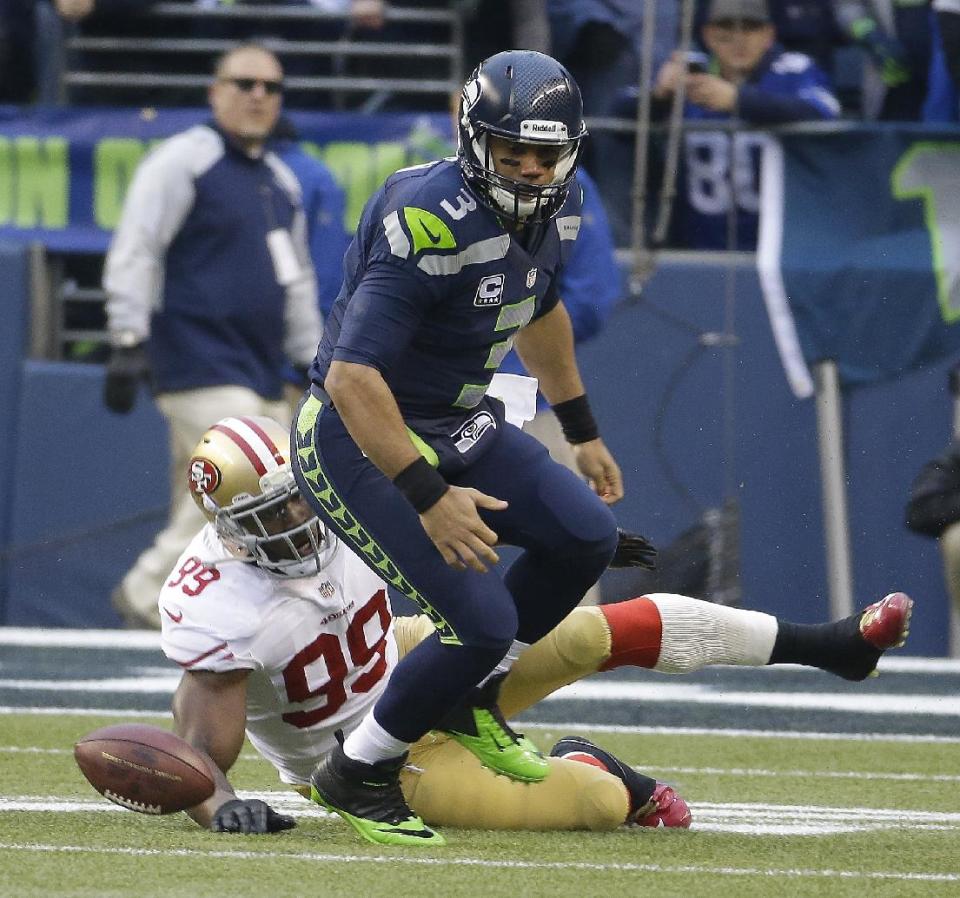 Seattle Seahawks' Russell Wilson (3) fumbles as he is hit by San Francisco 49ers' Aldon Smith (99) during the first half of the NFL football NFC Championship game Sunday, Jan. 19, 2014, in Seattle. (AP Photo/Ted S. Warren)