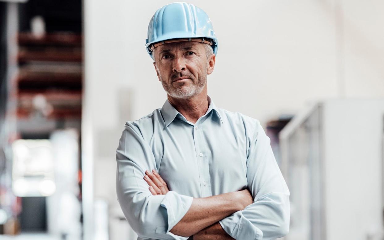 Confident male engineer standing with arms crossed in industry