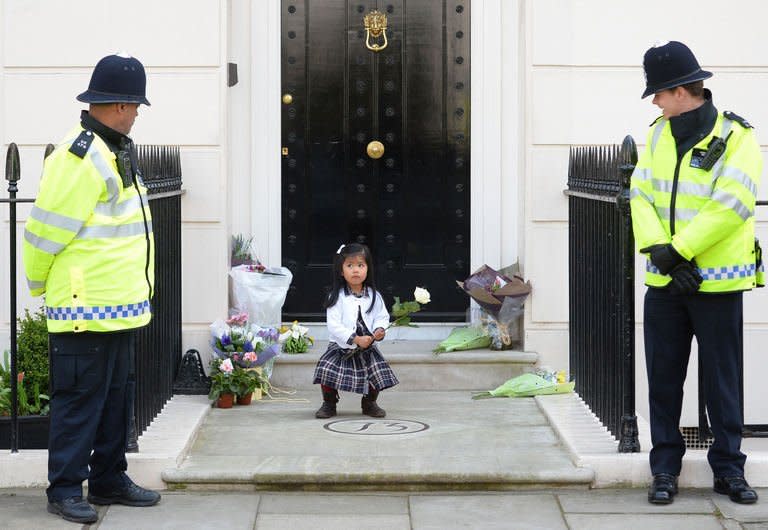 British police look on as a girl holds a rose amid floral tributes at the home of former British prime minister Margaret Thatcher in central London on April 10, 2013