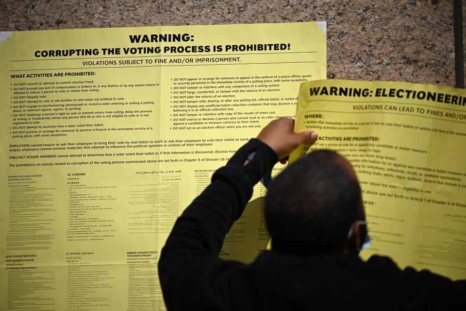 Poll workers hang signs warning against election fraud outside a polling station in Los Angeles on Nov. 1, 2022.