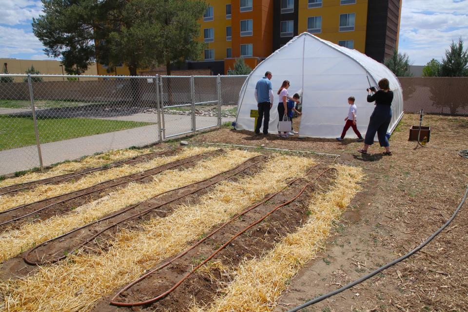 Visitors peek inside the greenhouse in the community garden at Animas Elementary School on Monday, April 22.