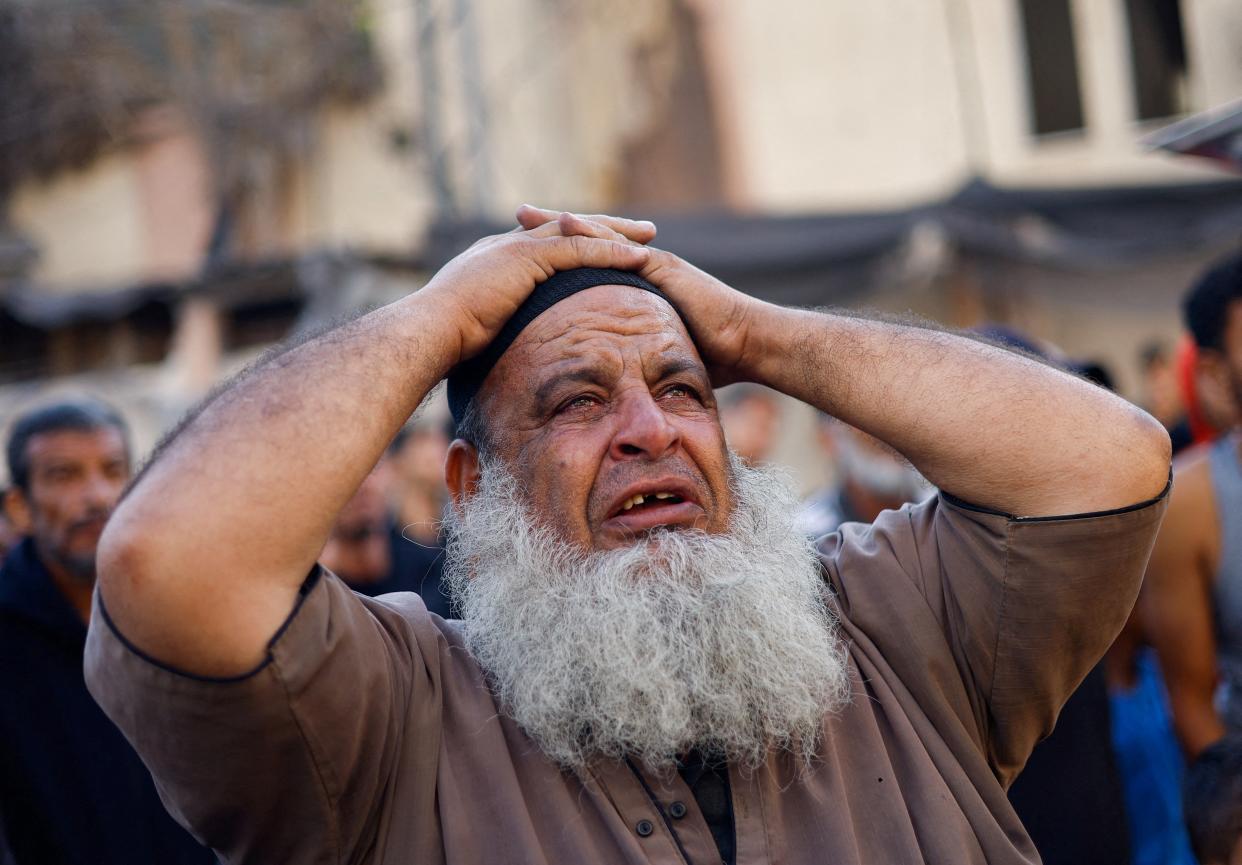 A Palestinian man reacts as people search for casualties under the rubble of a building destroyed by Israeli strikes in Khan Younis (Mohammed Salem/Reuters)