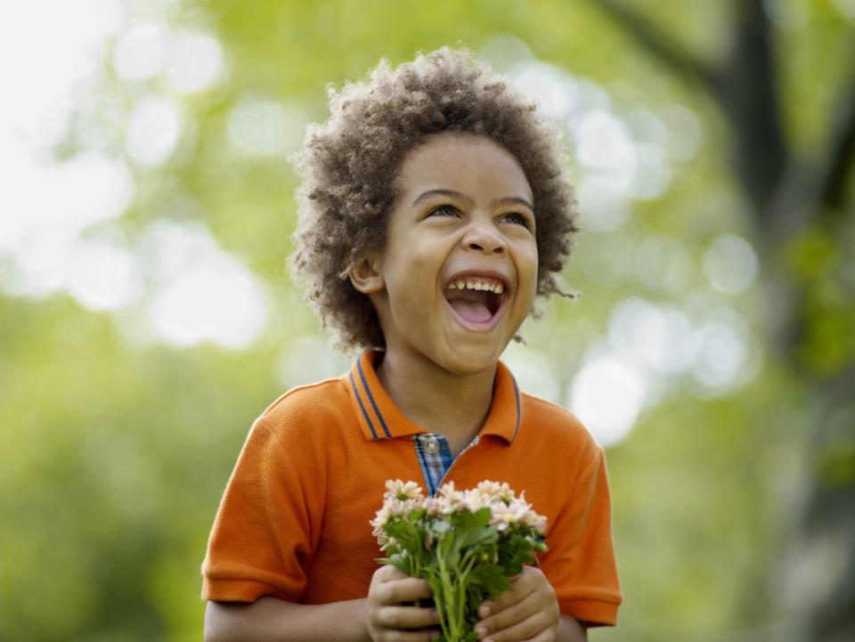 Boy (3-5) holding flower, laughing