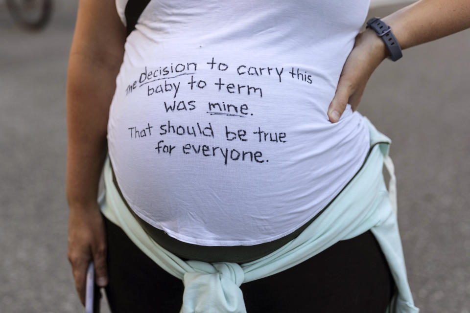 A pregnant protester is pictured with a message on her shirt in support of abortion rights during a march, Friday, June 24, 2022, in Seattle. The U.S. Supreme Court's decision to end constitutional protections for abortion has cleared the way for states to impose bans and restrictions on abortion — and will set off a series of legal battles. (AP Photo/Stephen Brashear)