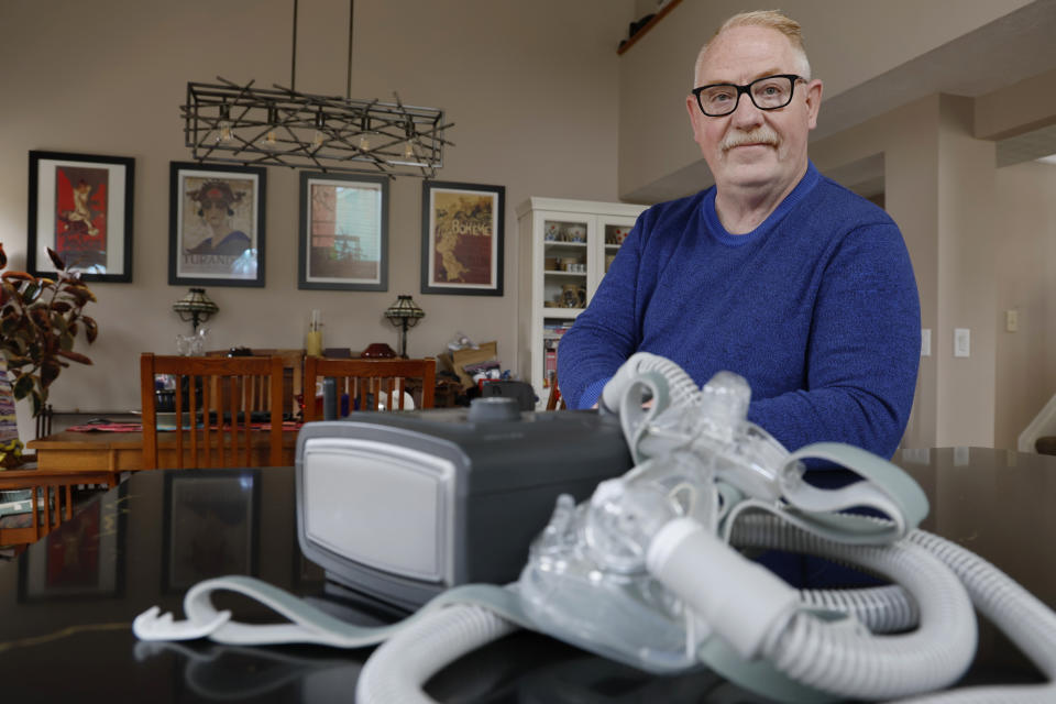 FILE - Jeffrey Reed, who experienced persistent sinus infections and two bouts of pneumonia while using a Philips CPAP machine, poses with the device at his home, Oct. 20, 2022, in Marysville, Ohio. On Monday, Jan. 29, 2024, Philips, the company behind a global recall of sleep apnea machines, said it will stop selling the devices in the U.S., under a tentative agreement with regulators that could cost the company nearly $400 million. (AP Photo/Jay LaPrete, File)