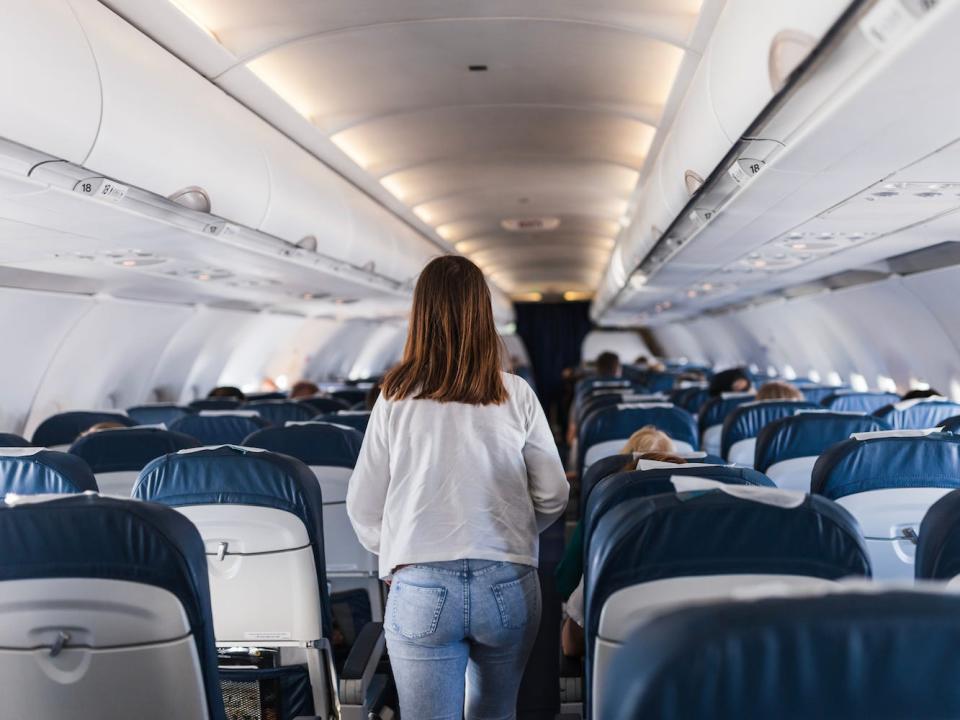 A person walks down an airplane aisle.