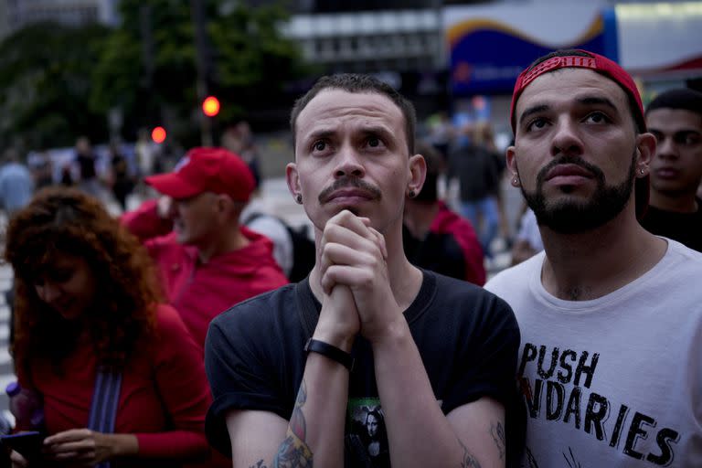 Seguidores del expresidente brasileño Luiz Ignacio Lula da Silva, quien vuelve a postularse para presidente, ven en una pantalla los resultados parciales luego del cierre de las urnas para las elecciones generales en Sao Paulo, Brasil, el domingo 2 de octubre de 2022. (Foto AP/Matias Delacroix )