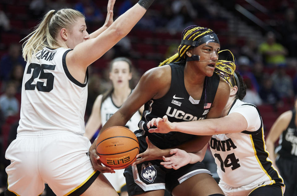 UConn forward Aaliyah Edwards (3) dribbles between Iowa forward Monika Czinano, left, and forward McKenna Warnock during the first half of an NCAA college basketball game in the Phil Knight Legacy Championship in Portland, Ore., Sunday, Nov. 27, 2022. (AP Photo/Craig Mitchelldyer)