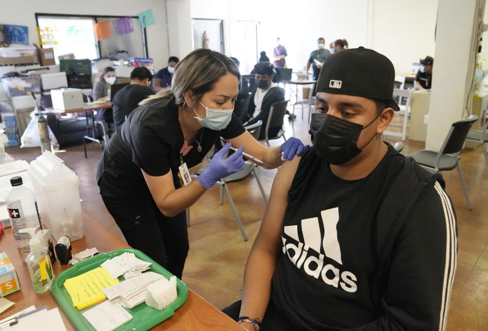 Geovany Parra, 18, gets his COVID-19 vaccine booster from medical assistant Mariela Rodriguez during a clinic at Promise Arizona's office in Phoenix on Jan. 26, 2022. First and second shots of the COVID-19 vaccine were free for ages 5 years old and up, as well as booster shots for all eligible.