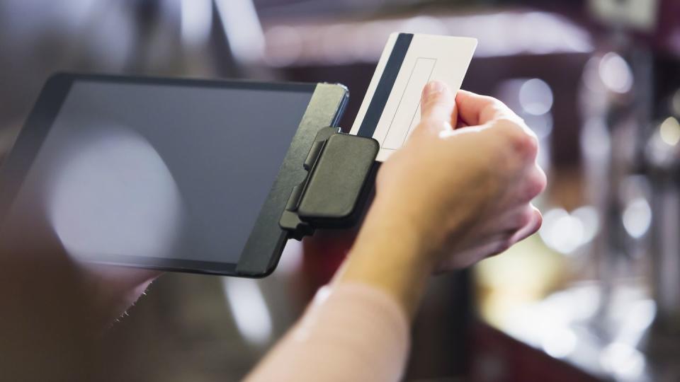 Hand of woman sliding credit card through reader