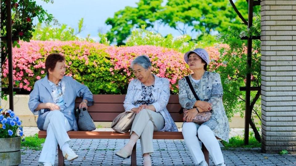 Tres mujeres de la tercera edad sentadas en un banco.