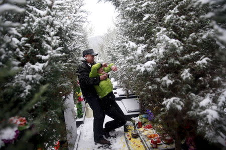 Fan Guohui comforts his wife Zheng Qing as they show their son's resting place to reporters on their visit to the graveyard in Zhangjiakou, REUTERS/Kim Kyung-Hoon