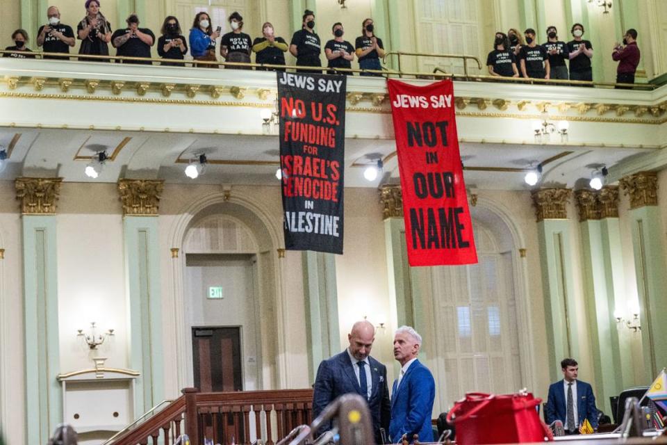 Assembly members Heath Flora, R-Ripon, and Josh Lowenthal, D-Long Beach stand on the California Assembly floor as protesters calling for a cease-fire in the Israel-Hamas war demonstrate in the gallery Wednesday. The demonstration shut down the Legislature’s first Capitol floor session of the new year.