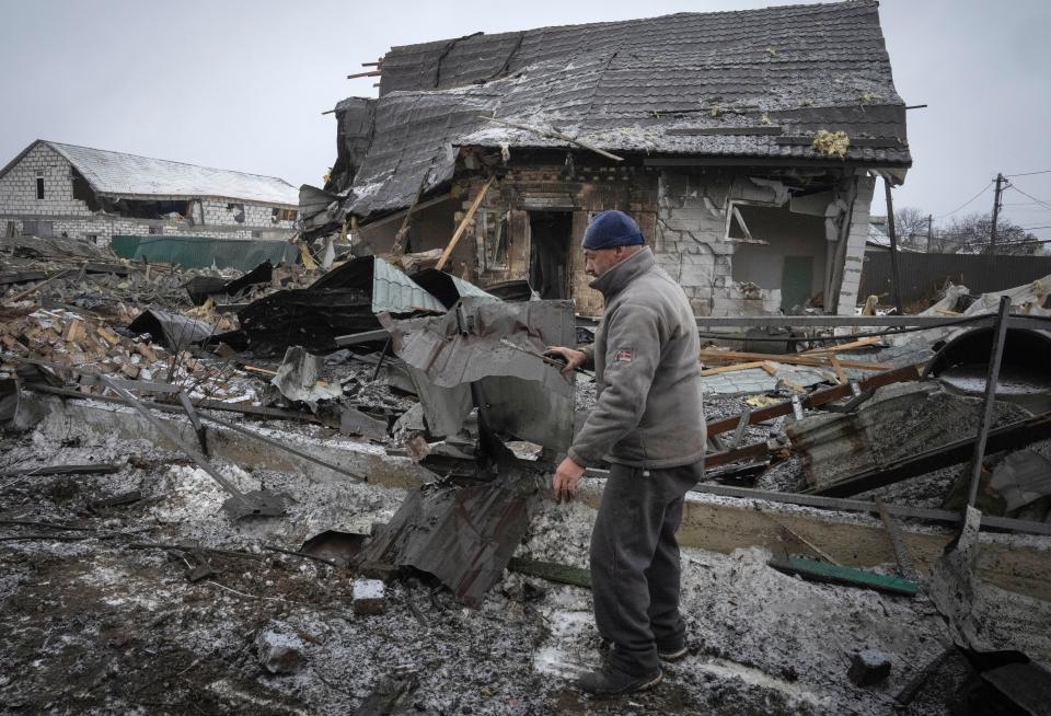 A local resident sorts out debris at the site of a private house ruined in the Russian missile attack in Kyiv, Ukraine, Monday, Dec. 11, 2023.