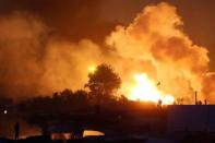 Migrants are seen in silhouette as they gather near flames from a burning makeshift shelter on the second day of the evacuation of migrants and their transfer to reception centers in France, as part of the dismantlement of the camp called the "Jungle" in Calais, France, October 25, 2016. REUTERS/Pascal Rossignol