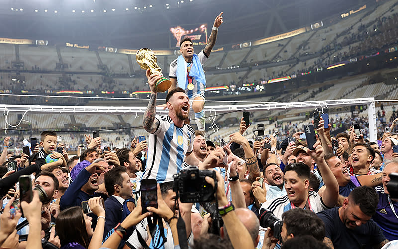 Lionel Messi of Argentina celebrates with teammates, fans and the FIFA World Cup trophy after the team’s victory in the final over France at Lusail Stadium on Dec. 18 in Lusail City, Qatar. <em>Clive Brunskill/Getty Images</em>