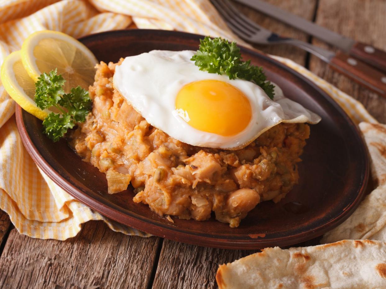 ful medames with a fried egg and pita close up on the table. horizontal