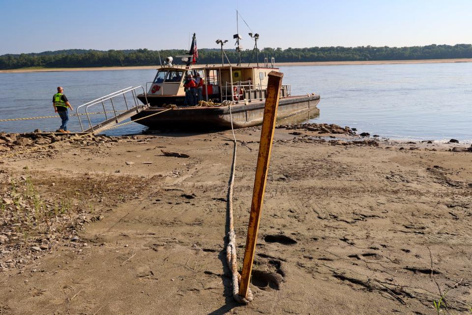 Dredge workers hike down a muddy shore, far upstream on the Mississippi, where this fall has brought critically low river levels.