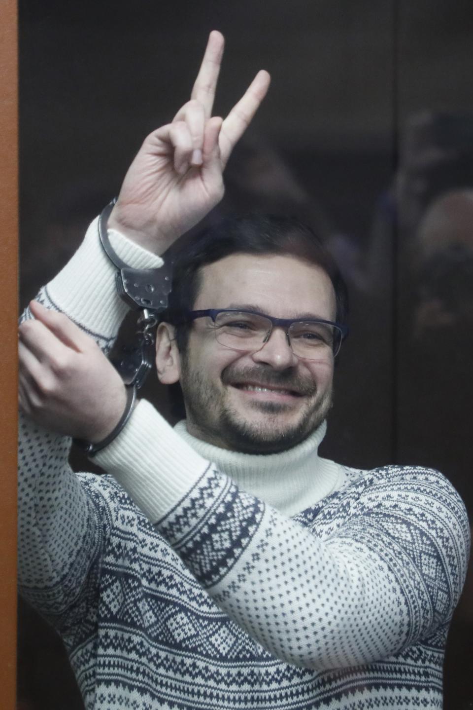 Russian opposition activist and former municipal deputy of the Krasnoselsky district Ilya Yashin gestures, smiling as he stands inside a glass cubicle in a courtroom, prior to a hearing in Moscow, Russia, Friday, Dec. 9, 2022. Yashin faces a trial on charges stemming from his criticism of the Kremlin's action in Ukraine. (Yury Kochetkov/Pool Photo via AP)