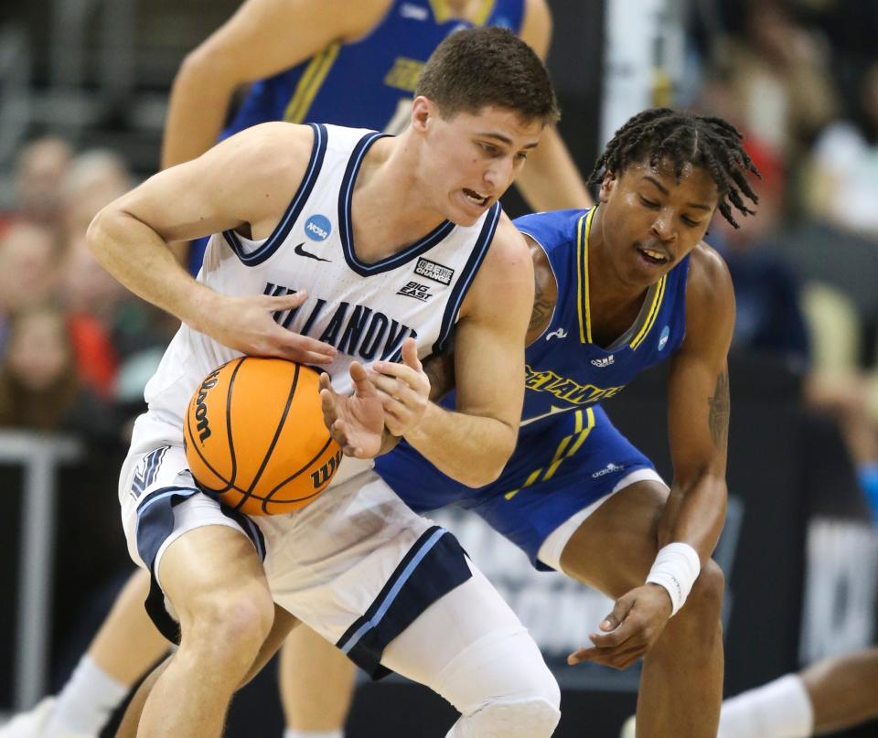Delaware's Kevin Anderson (right) chips away at the ball but can't separate it from Villanova's Collin Gillespie in the first half of a first round matchup in the NCAA tournament at PPG Paints Arena in Pittsburgh, Pa., Friday, March 18, 2022.