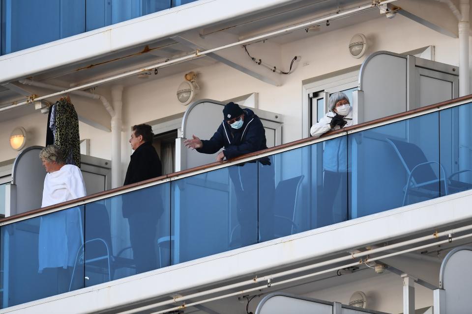 Passengers stand on balconies on the Diamond Princess cruise ship, with around 3,600 people quarantined onboard due to fears of the new coronavirus, at the Daikoku Pier Cruise Terminal in Yokohama port on February 10, 2020. - Around 60 more people on board the quarantined Diamond Princess cruise ship moored off Japan have been diagnosed with novel coronavirus, the country's national broadcaster said on February 10, raising the number of infected passengers and crew to around 130. (Photo by CHARLY TRIBALLEAU / AFP) (Photo by CHARLY TRIBALLEAU/AFP via Getty Images)