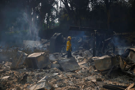 A firefighter stands in the debris of a home destroyed by the Woolsey Fire in Malibu, California, U.S. November 10, 2018. REUTERS/Eric Thayer