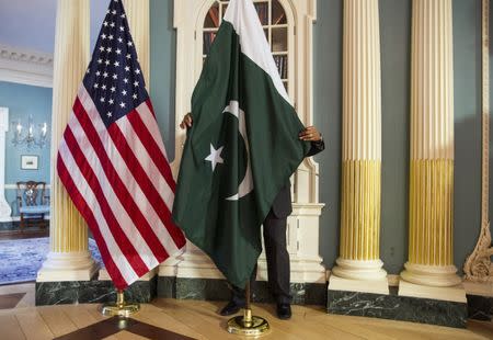 A State Department contractor adjust a Pakistan national flag before a meeting between U.S. Secretary of State John Kerry and Pakistan's Interior Minister Chaudhry Nisar Ali Khan on the sidelines of the White House Summit on Countering Violent Extremism at the State Department in Washington February 19, 2015. REUTERS/Joshua Roberts