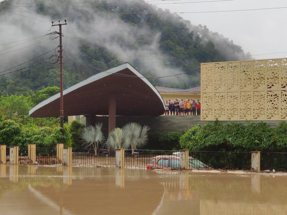 Hotel guests stand on the roof of Lemon Tree hotel, as the hotel gets flooded with the waters from an overflowing Kosi River in Jim Corbett National Park, Uttarakhand state, Tuesday, Oct. 19, 2021. More than 20 people have died and many are missing in floods triggered by heavy rains in the northern Indian state of Uttarakhand, officials said Tuesday. (AP Photo/Mustafa Quraishi)