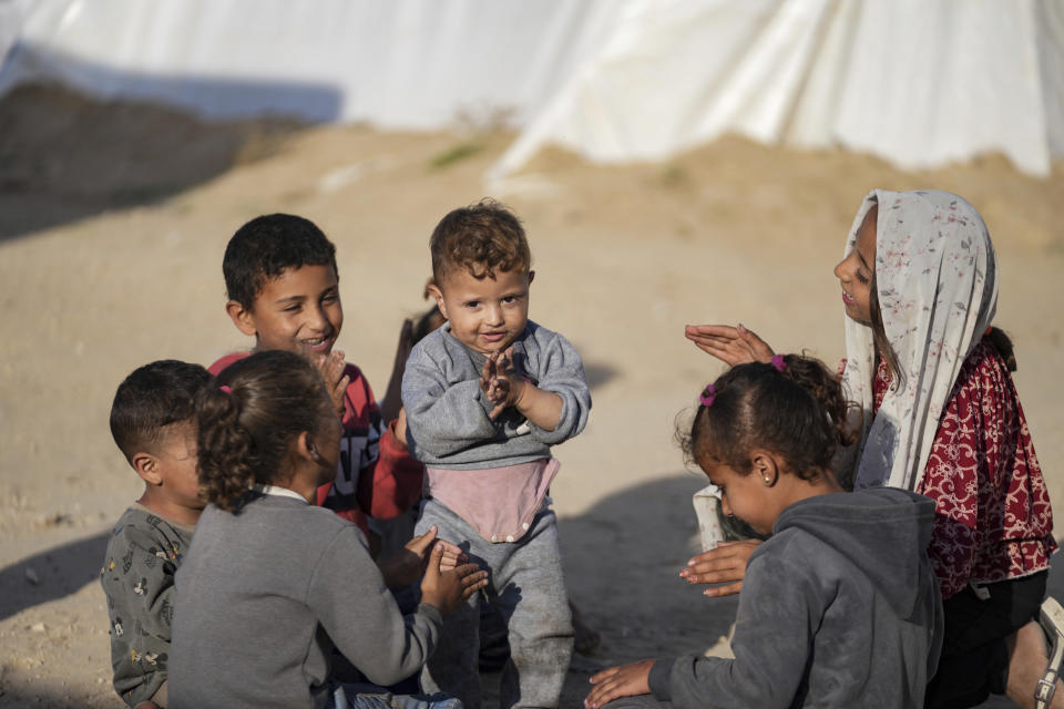 Palestinian children, displaced by the Israeli air and ground offensive on the Gaza Strip, play together as they stand at a makeshift tent camp in Deir al Balah, Monday, May 13, 2024. Palestinians on Wednesday, May 15, 2024, will mark the 76th year of their mass expulsion from what is now Israel. It's an event that is at the core of their national struggle, but in many ways pales in comparison to the calamity now unfolding in Gaza. (AP Photo/Abdel Kareem Hana)