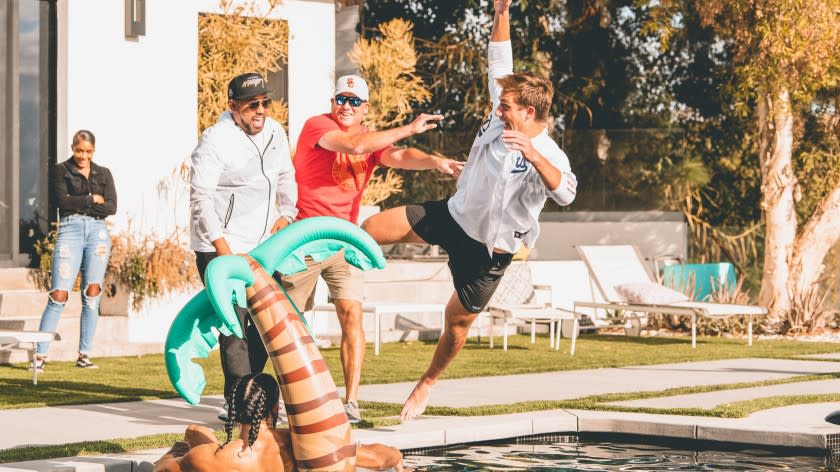 USC coach Clay Helton pushes quarterback Kedon Slovis in the pool next to director of player development Gavin Morris.